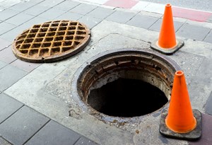 manhole surrounded by 2 orange safety cones 